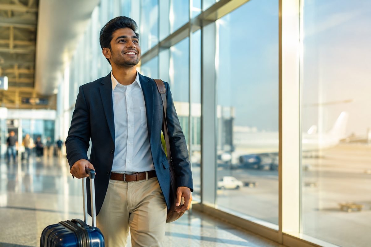Young Indian professional with a suitcase at an airport departure gate